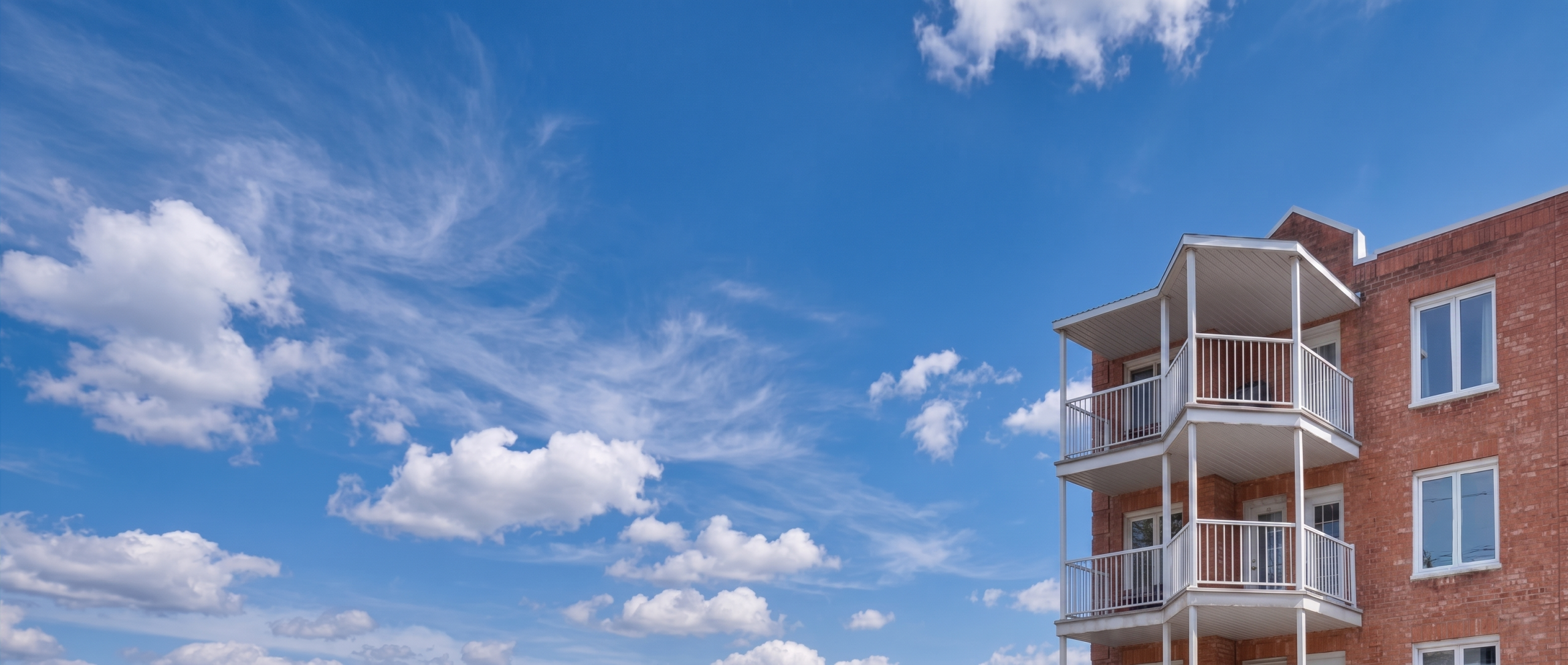 Immeuble résidentiel, balcons blancs, ciel bleu